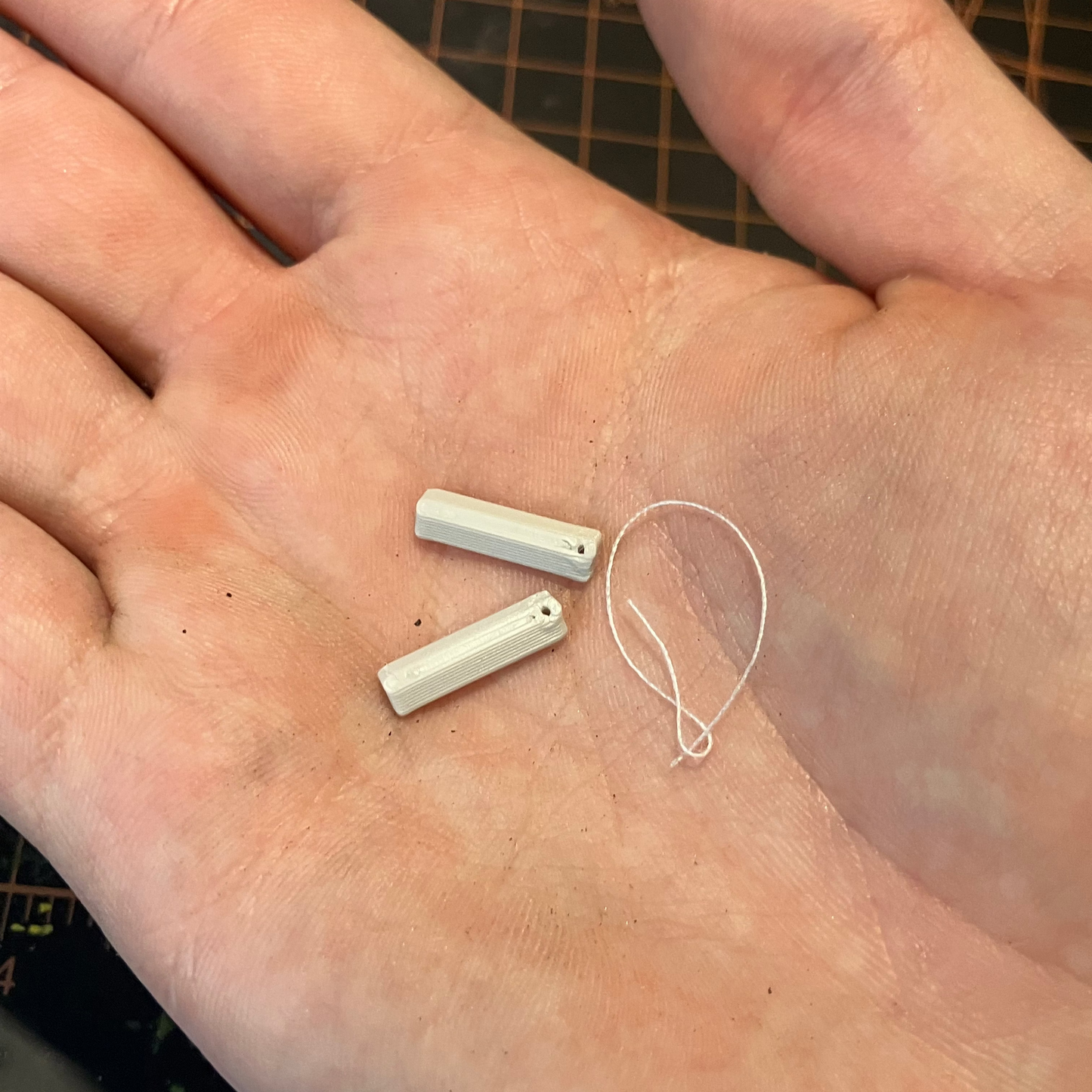 A set of unpainted scale model wheel chocks in the palm of a hand.
